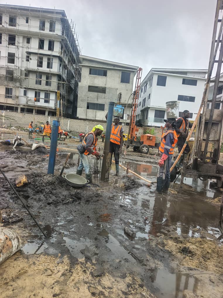 Crew working on pile caps in front of a completed building